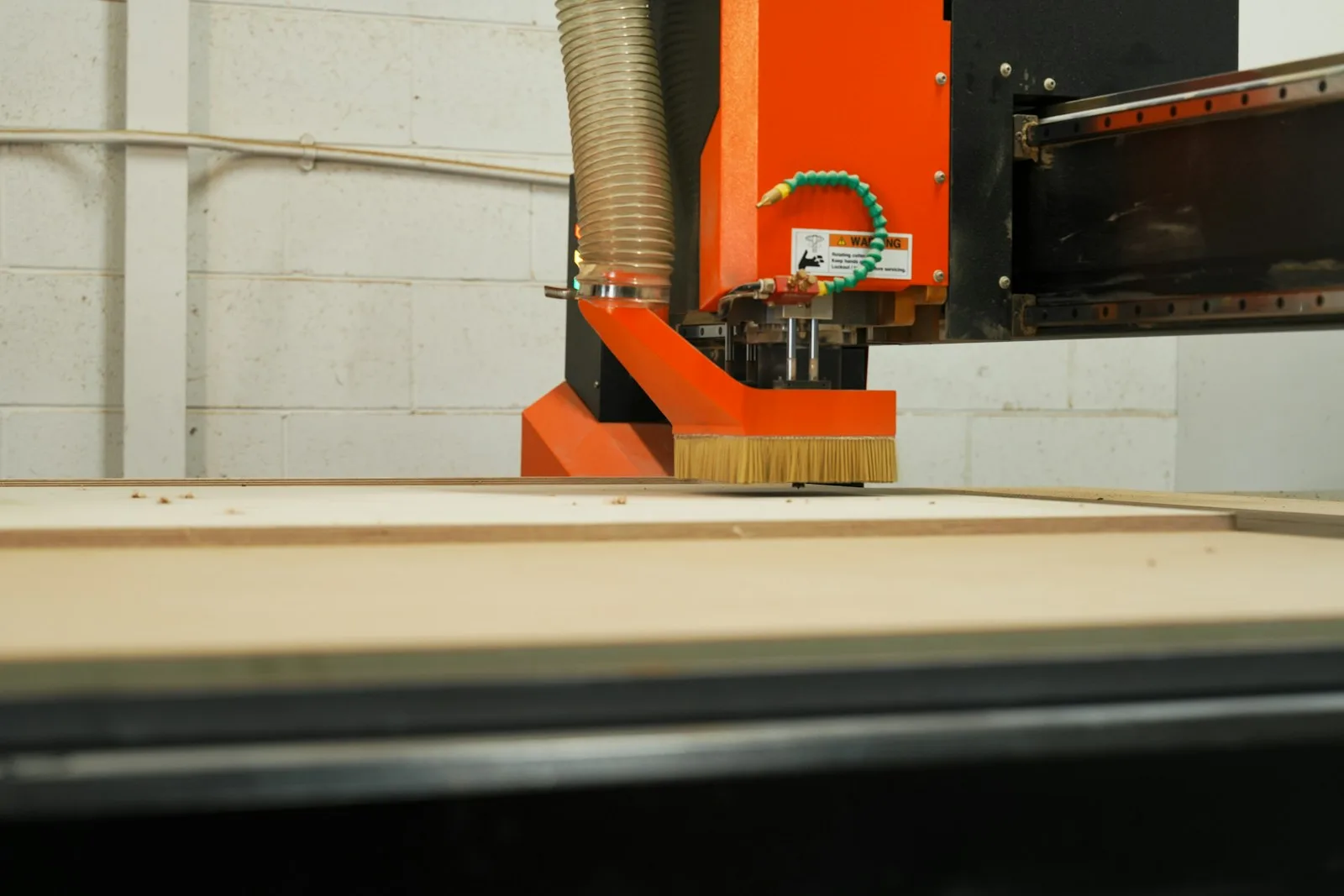 Fresa CNC com escova a trabalhar um painel de madeira.